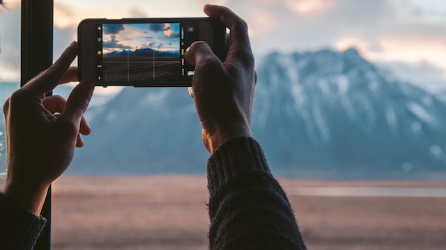 person holding black smartphone taking photo of mountain during daytime